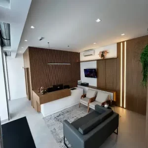 Recepção da Clínica Vertz com design moderno, sofá cinza, poltronas claras, balcão de atendimento em madeira.